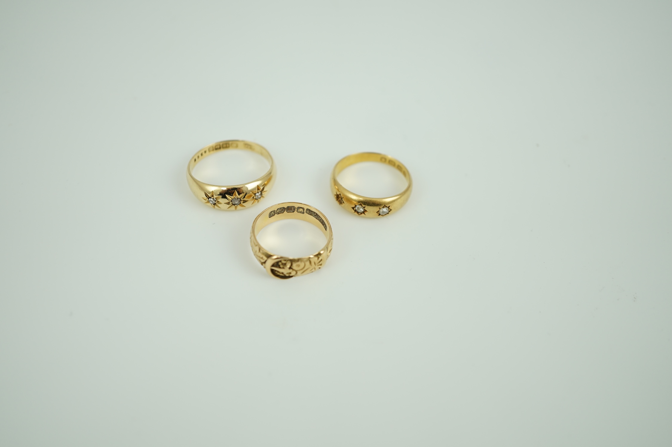 A Victorian 18ct gold buckle ring, size K/L, a Victorian 18ct gold and gypsy set three stone diamond ring (stone missing) and a later 18ct gold and gypsy set three stone diamond ring